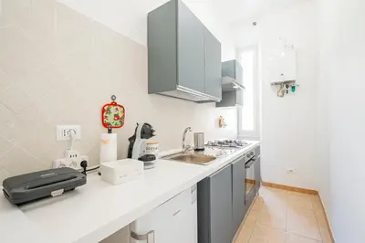 a white kitchen with a sink and a counter at Lilli's Home Garbatella in Rome