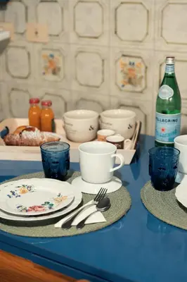 a blue counter with plates and cups and utensils at Celeste Suite Reginella in Rome