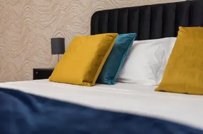 a bed with yellow and blue pillows on it at Trastevere suites Luxury Garden Retreat in Rome