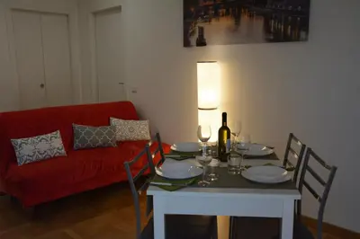 a dining room with a table and a red couch at VMV Holiday houses in Rome