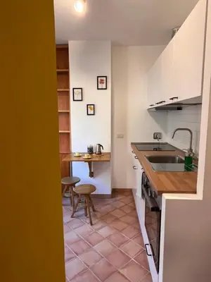 a kitchen with white cabinets and a sink and a table at Sampietrino Vatican Apartment in Rome