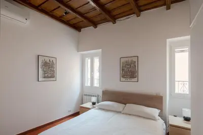a white bedroom with a bed and two windows at Colosseum Apt in Rome
