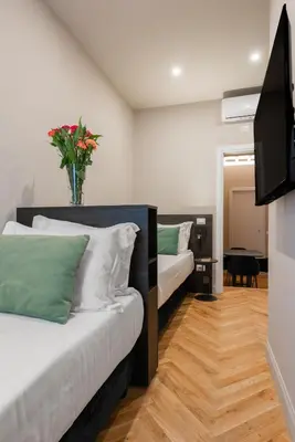 a bedroom with two beds and a vase of flowers at H77 Apartments - Maison D'Art Collection in Rome