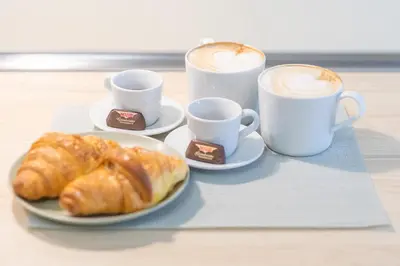 two cups of coffee and two plates of croissants at St Peter's Comfort Lodge in Rome