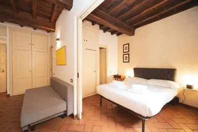 a bedroom with a large white bed and a chair at Trevi Fountain by BuddyRent in Rome
