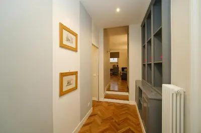 a hallway with white walls and wood floors at Castel Sant'Angelo by BuddyRent in Rome