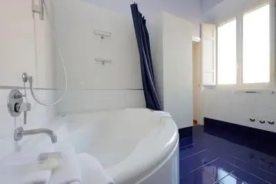 a white bathroom with a tub and a window at Vatican Luxury Apartment in Rome