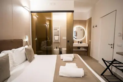 a bedroom with a large white bed and a bathroom at Cicerone's Luxury Suites in Rome