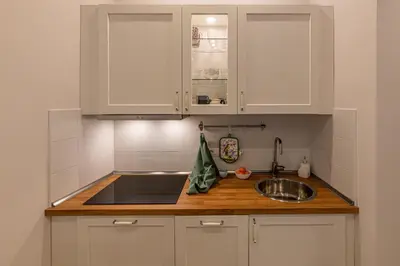 a kitchen with white cabinets and a sink at San Peter's Country House in Rome