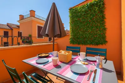 a table with chairs and an umbrella on a balcony at Stylish duplex with terrace Rome in Rome