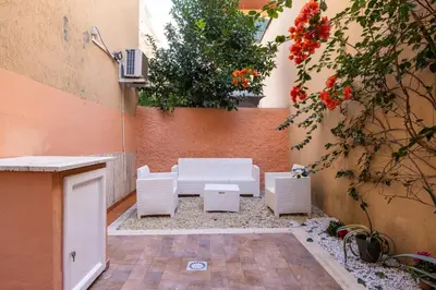 a patio with white chairs and a table and flowers at CASA GIOVI - Apartment with garden in Rome