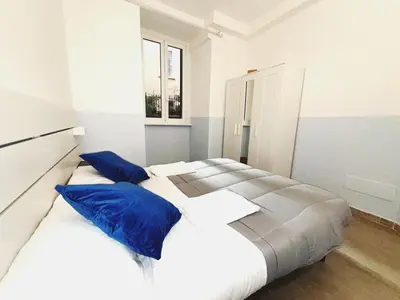 a white bedroom with two beds with blue pillows at Scala Santa Home in Rome