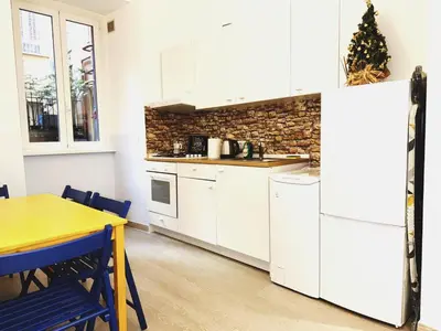 a kitchen with white cabinets and a yellow table and a table and a refrigerator at Scala Santa Home in Rome