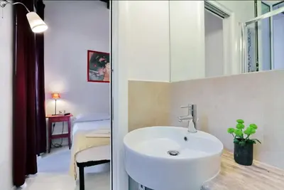 a bathroom with a white sink and a bedroom at Campo de fiori charm apartment in Rome