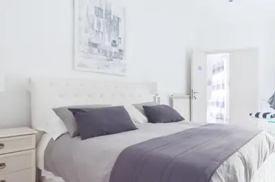 a white bedroom with a large bed with purple pillows at Veneto Excelsior Suite in Rome