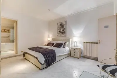a white bedroom with a bed and a bathroom at Veneto Excelsior Suite in Rome
