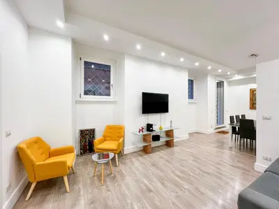 a living room with yellow chairs and a flat screen tv at LA CORTE at the Colosseum in Rome