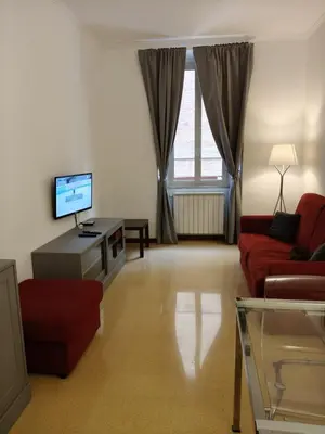 a living room with a red couch and a tv at Vatican Home Borgo Pio II in Rome