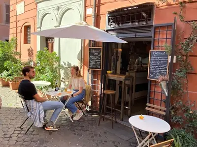 two people sitting at a table outside of a restaurant at Amazing Terrace in Trastevere in Rome