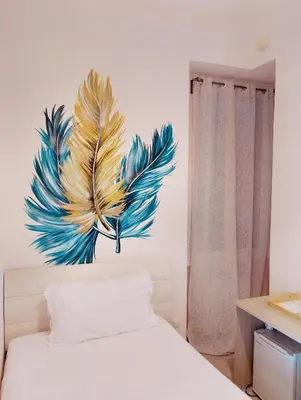a bedroom with a painting of a feather on the wall at San Giovanni Rooms Roma in Rome