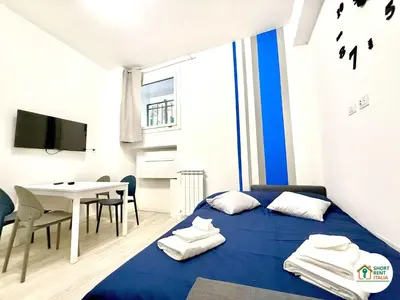 a bedroom with a blue bed and a table and a tv at Re di Roma - Colosseo House in Rome