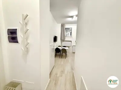 a hallway with white walls and a dining room with a table at Re di Roma - Colosseo House in Rome