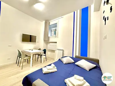 a bedroom with a blue bed and a table with chairs at Re di Roma - Colosseo House in Rome