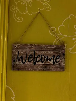 a welcome sign is hanging on a yellow wall at CasaPigneto34 in Rome