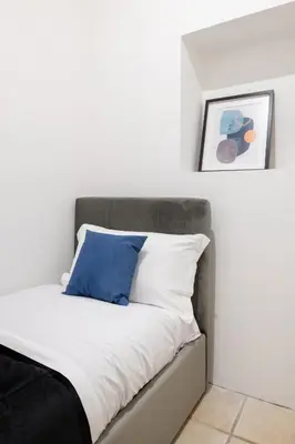 a bed with white sheets and a blue pillow at V HOME San Lorenzo in Rome