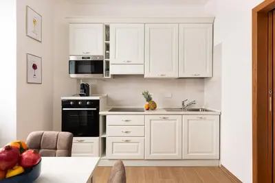 a white kitchen with white cabinets and a sink at Idyllia - Magnificent Central Apartment in Rome