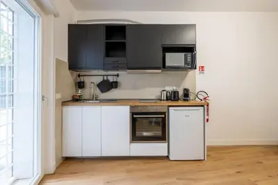 a kitchen with white cabinets and black appliances at Little House 15 in Rome