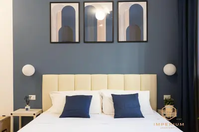 a bedroom with a white bed with blue pillows at Imperium Luxury Suites - 100mt to Metro A, 5 min to center, pvt bathroom, A-C in Rome