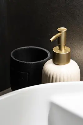 a white bottle with a brass nozzle next to a vase at Imperia House in Rome