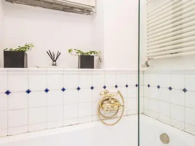 a bathroom with white tiled walls and a tub at Luxury Spanish Steps Terrace in Rome