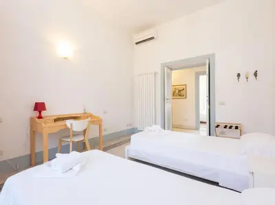 two beds in a room with a desk and a table at Vatican Comfortable Sunny Apartment in Rome