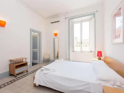 a white bedroom with a large white bed and windows at Vatican Comfortable Sunny Apartment in Rome