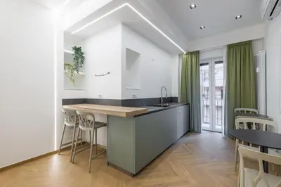 a kitchen with white walls and a counter and chairs at Hezio Guest House in Rome