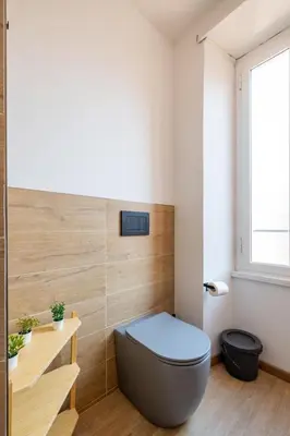 a bathroom with a blue toilet and a window at cRoma - guest house in Rome