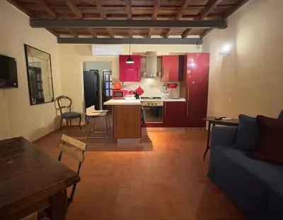 a living room with a couch and a kitchen with red cabinets at Casa dolce Casa Trastevere in Rome