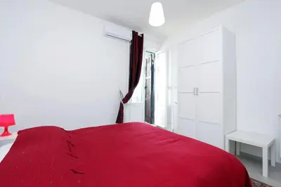 a red bed in a white room with a window at Bright Vatican 2 bedroom Apartment in Rome