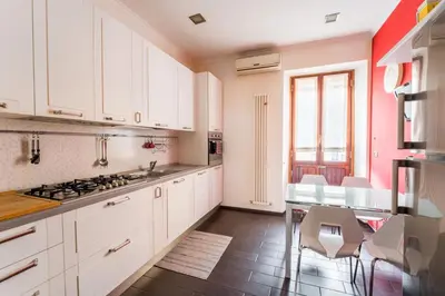 a kitchen with white cabinets and a table with chairs at Dimora Esedra, Historical Flat in the Heart of Rome in Rome