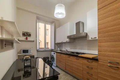 a kitchen with white walls and wooden cabinets at JOIVY Charming 3BR flat near the Vatican in Rome