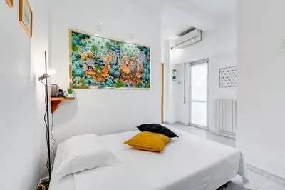 a white room with a bed with a painting on the wall at Casa San Paolo in Rome
