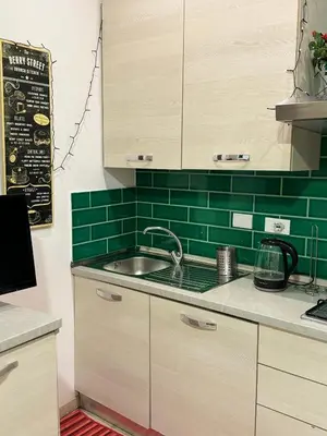 a kitchen with a sink and a green tiled wall at suite Colosseo in Rome