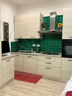 a kitchen with white cabinets and green tiles at suite Colosseo in Rome