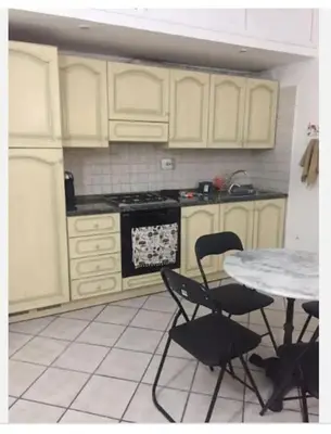 a kitchen with white cabinets and a table and chairs at Casa Adry in Rome