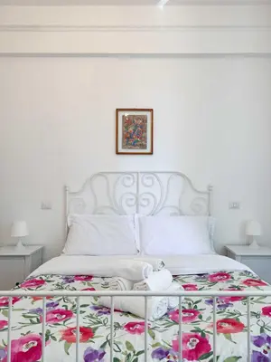 a bedroom with a white bed with a floral bedspread at Piramide Suites 2 Bedrooms & 2 Bathrooms in Rome