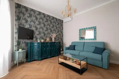 a living room with a blue couch and a tv at Olimpia House - Gianicolense in Rome