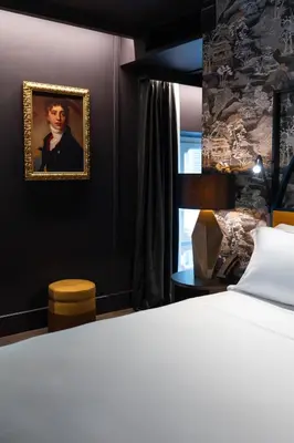 a bedroom with a bed and a portrait of a man at The Goethe Hotel - Small Luxury Hotels of the World in Rome