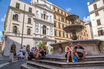 a group of people sitting on steps next to a fountain at Empire Loft in the shadow of Colosseum in Rome